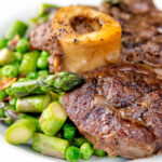 Close up braised beef shin with peas, asparagus and bacon.