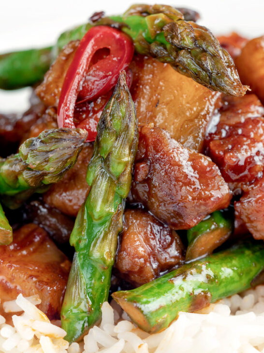 Close up Korean pork belly with a gochujang glaze and asparagus.