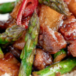 Close up Korean pork belly with a gochujang glaze and asparagus featuring a title overlay.