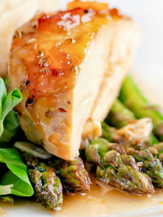 Close up orange marmalade chicken breast served with asparagus.