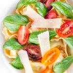 Overhead close up tomato consomme or brodo with tortellini and cherry tomatoes.