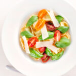 Overhead tomato consomme or brodo with tortellini and cherry tomatoes.