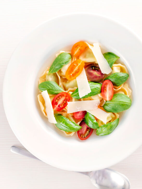 Overhead tomato consomme or brodo with tortellini and cherry tomatoes.