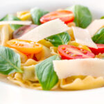 Close up tomato consomme or brodo with tortellini and cherry tomatoes.