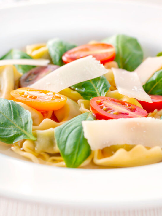 Close up tomato consomme or brodo with tortellini and cherry tomatoes.