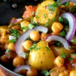 Indian chana aloo, a chickpea and potato curry served with red onion.