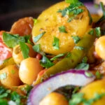 Close up chana aloo, an Indian chickpea and potato curry served with red onion.