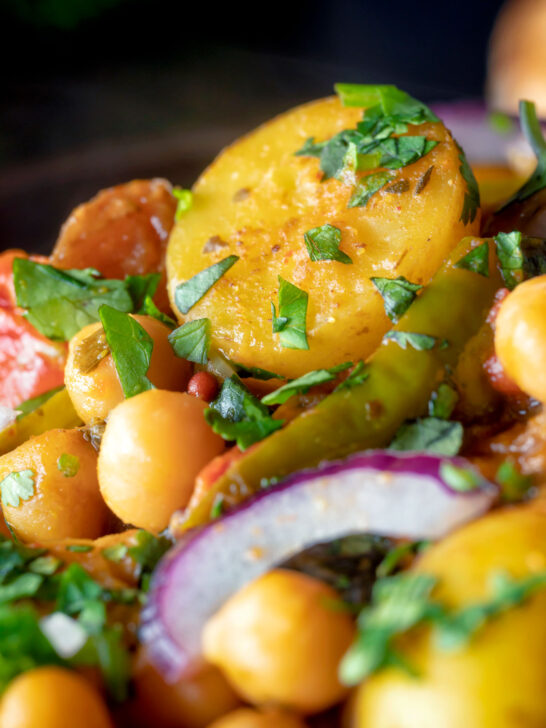 Close up chana aloo, an Indian chickpea and potato curry served with red onion.