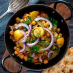 Overhead chana aloo, an Indian chickpea and potato curry served with red onion.