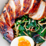 Close up overhead hoisin chicken breast ramen with Swiss chard and a soft boiled egg.