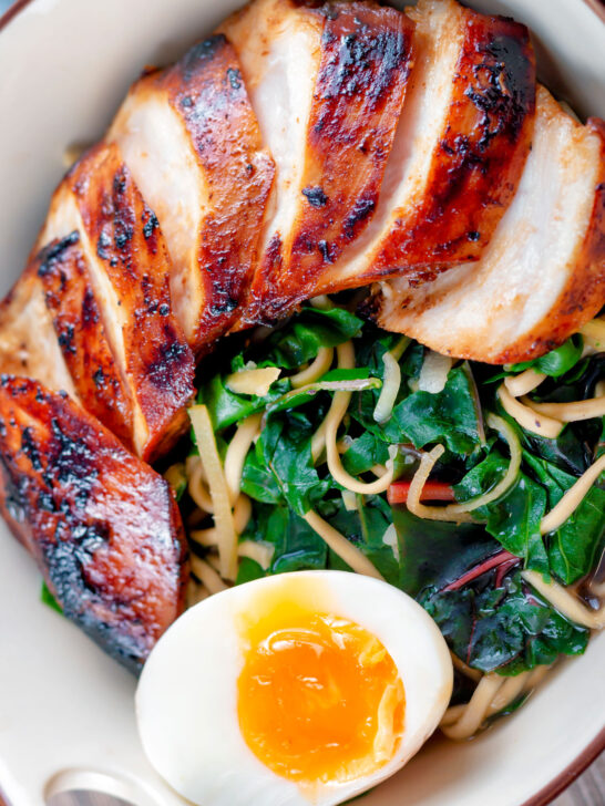 Close up overhead hoisin chicken breast ramen with Swiss chard and a soft boiled egg.
