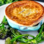 Puff pastry topped individual creamy chicken and leek pie served with broccoli.