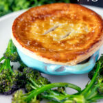 Puff pastry topped individual creamy chicken and leek pie served with broccoli featuring a title overlay.