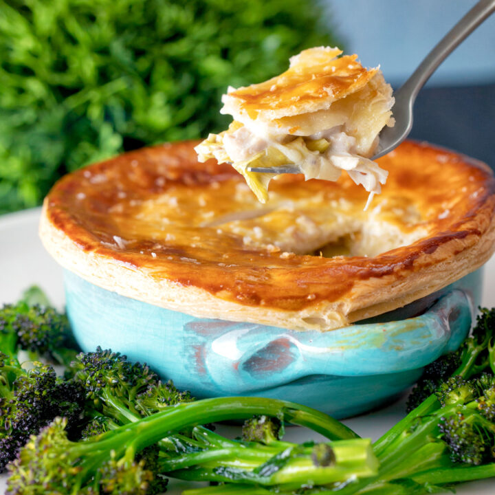 Puff pastry topped individual chicken and leek pie showing creamy filling.