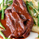 Close up lamb shoulder chops, red wine and tomato sauce with mash and green beans.