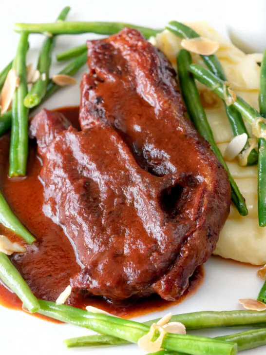 Close up lamb shoulder chops, red wine and tomato sauce with mash and green beans.