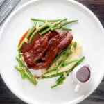 Overhead lamb shoulder chops, red wine and tomato sauce with mash and green beans.