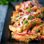 Masala chips or fries topped with onion, tomato, chilli and coriander featuring a title overlay.