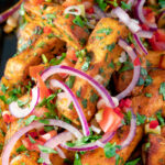 Close up masala chips or fries topped with onion, tomato, chilli and coriander.