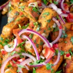 Close up masala chips or fries topped with onion, tomato, chilli and coriander.