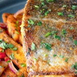 Close up crispy skinned masala fish fillet (coley) served with masala chips.