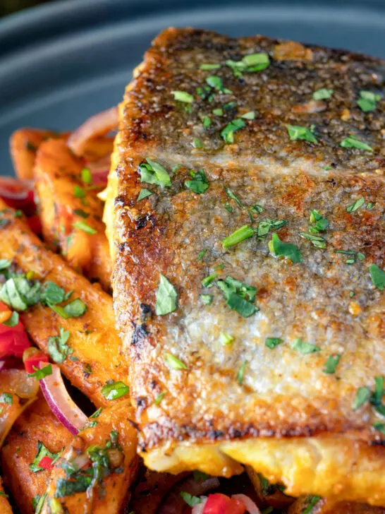 Close up crispy skinned masala fish fillet (coley) served with masala chips.