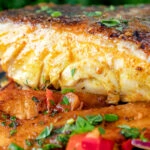 Close up masala fish fillet (coley) served with masala chips.