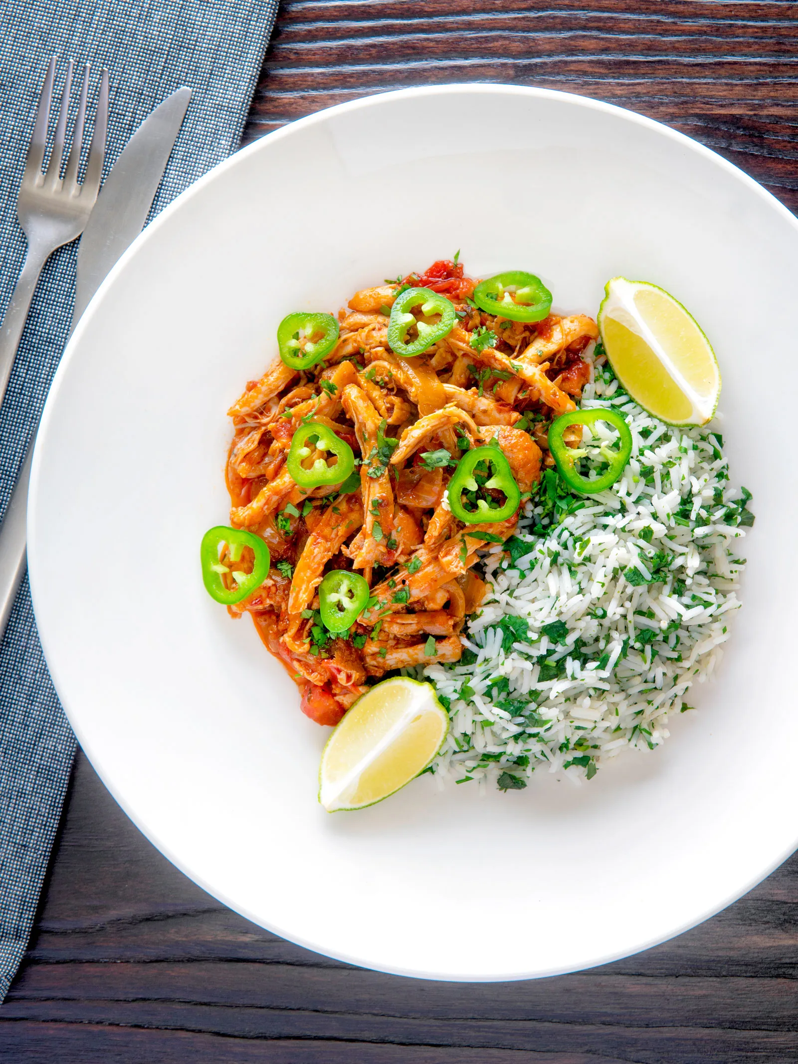 Overhead Mexican shredded chicken stew served with coriander rice and jalapenos.