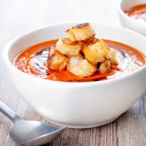 Homemade roasted garlic tomato soup with croutons and balsamic reduction.