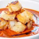 Close up garlic croutons served with homemade roasted garlic tomato soup.