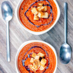 Two bowls of roasted tomato soup with garlic croutons and balsamic vinegar.