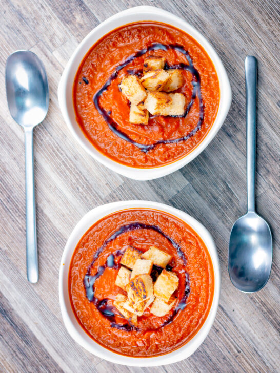 Two bowls of roasted tomato soup with garlic croutons and balsamic vinegar.