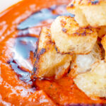 Close up roasted tomato soup with garlic croutons and balsamic vinegar.