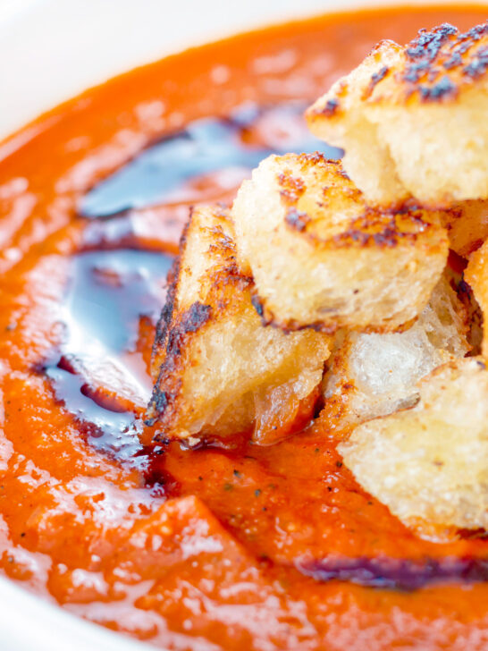 Close up roasted tomato soup with garlic croutons and balsamic vinegar.