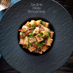 Overhead canned sardine pasta Bolognese with mezzi rigatoni and fresh dill featuring a title overlay.