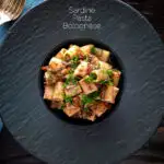Overhead canned sardine pasta Bolognese with mezzi rigatoni and fresh dill featuring a title overlay.