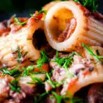 Close up canned sardine pasta Bolognese with mezzi rigatoni and fresh dill featuring a title overlay.