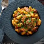 Overhead sausage gnocchi in a tomato sauce with fresh parsley featuring a title overlay.