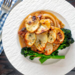 Overhead potato topped sausage hotpot with cider onion gravy served with broccoli featuring a title overlay.