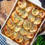 Overhead crispy scalloped potato topped sausage hotpot with cider onion gravy.