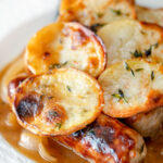 Close up potato topped sausage hotpot with cider onion gravy.