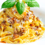 Slow cooker bolognese sauce served with tagliatelle pasta and fresh basil.