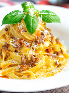 Slow cooker bolognese sauce served with tagliatelle pasta and fresh basil.