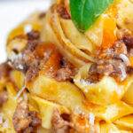 Close up slow cooker bolognese sauce served with tagliatelle pasta and parmesan.