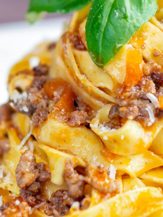 Close up slow cooker bolognese sauce served with tagliatelle pasta and parmesan.