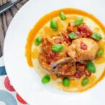 Overhead lighter slow cooker chicken cacciatore served with cheesy polenta.