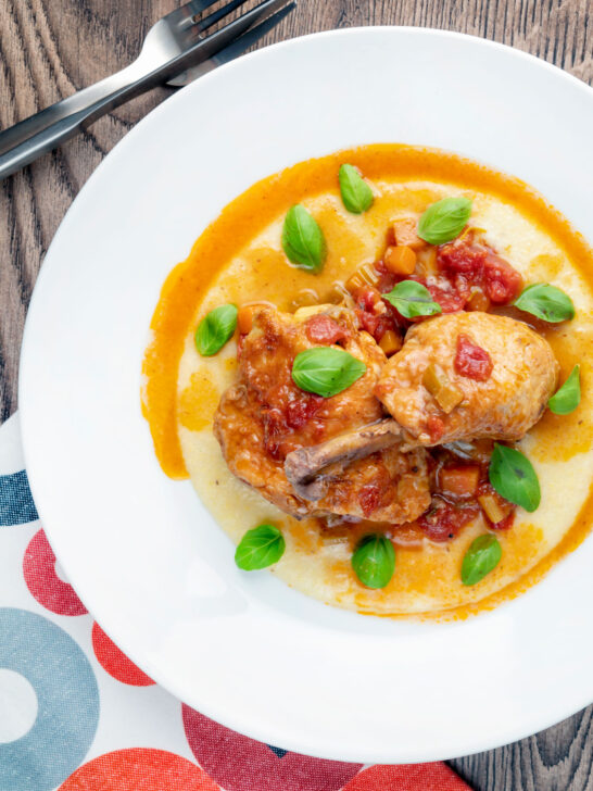 Overhead lighter slow cooker chicken cacciatore served with cheesy polenta.