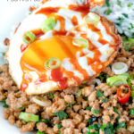 Close up of a sriracha fried egg served with Thai minced pork featuring a title overlay.