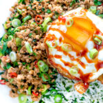 Close up Thai minced pork with coriander rice and a fried egg.