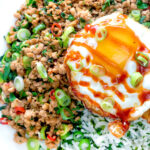 Close up Thai minced pork with coriander rice and a fried egg featuring a title overlay.